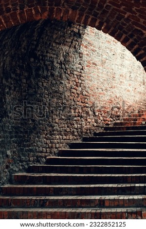 Vintage brickwork passageway with staircase leading to the light exit, selective focus