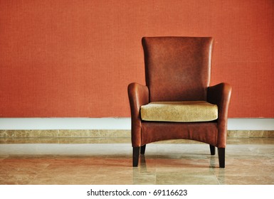 벽 옆에 서 있는 빈티지 갈색 의자 스톡 사진