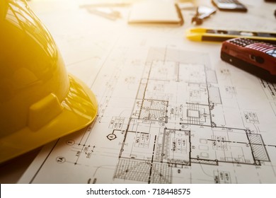 Vintage business desk of engineer contractor with equipment, blueprint, safety helm and object. - Shutterstock ID 718448575
