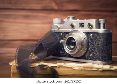 Vintage camera with 35mm film on old book over wooden defocused background