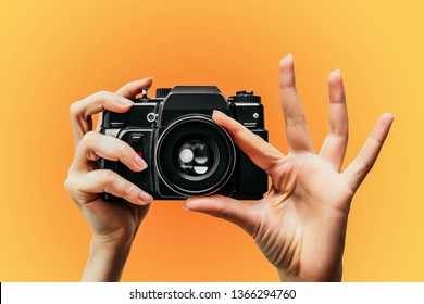 Vintage Camera in female hand. A photo. Photographer. Manual focus. Colored background. orange