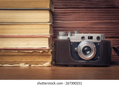 Vintage Camera and Stack of Books Over Wooden  Background