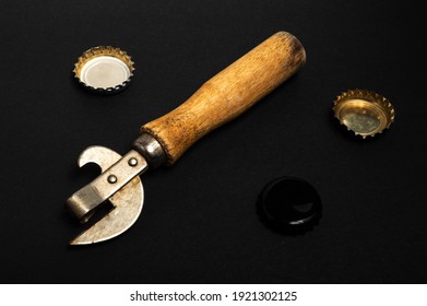 Vintage Can Opener And Beer Corks On A Black Surface. High Quality Photo