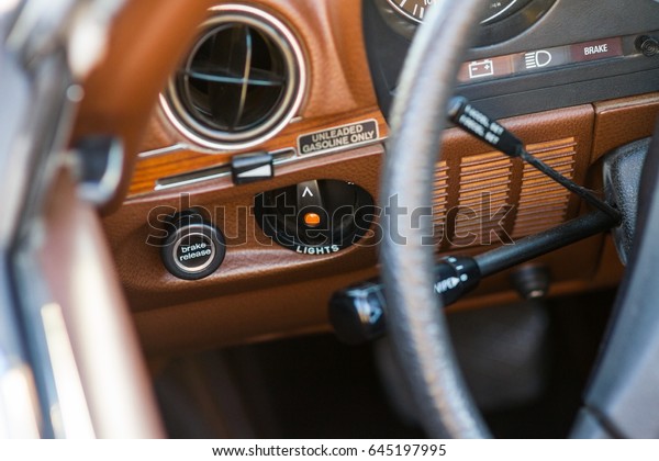 Vintage\
car brown interior focusing on the light switch with the air vent,\
steering wheel and indicator in the background\
