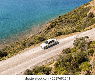 Vintage Car Driving Along a Coastal Road by the Sea - Powered by Shutterstock