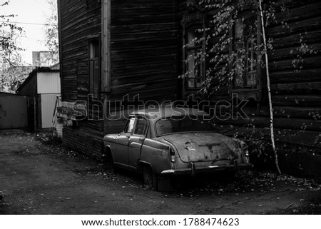 Vintage car near the wooden hause in Tomsk, Siberia. Black and white photo.
