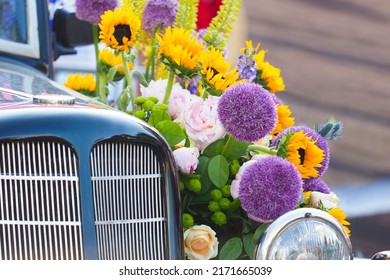 Vintage car wedding decoration. Retro car adorned with beautiful pink, violet and orange flowers. Luxury wedding car, just married