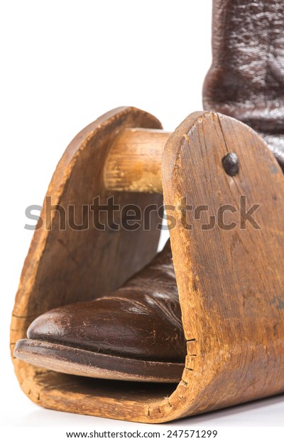 Vintage Caribou\
Hide Cowboy Boot in antique homemade wooden saddle stirrup against\
white background with copy\
space.