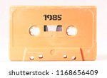 A vintage cassette tape from the 1980s era (obsolete music technology) labeled 1985 (my addition, not in the original image). Color: cream, sand. White background.
