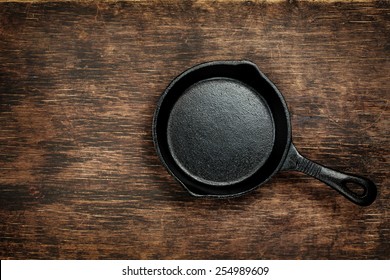 Vintage cast iron skillet on rustic wood background. Food background with copyspace