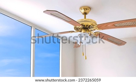 Vintage ceiling fan with electric lamps hanging on ceiling inside of white room