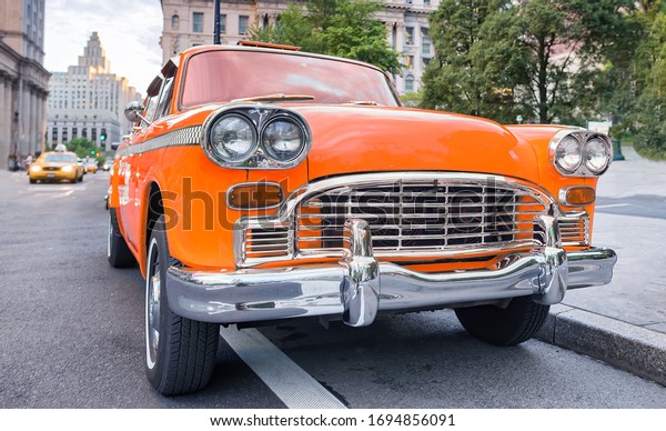 Vintage chequered orange taxi cab in New York\
City. Manhattan street\
traffic.