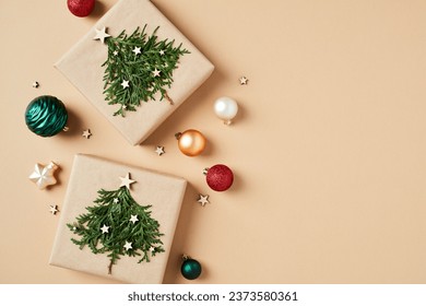 Vintage Christmas card design with craft paper gift boxes with Christmas trees and colorful Xmas balls on beige background. Flat lay. Top view. - Powered by Shutterstock