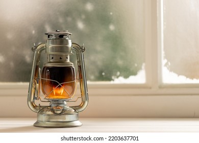 Vintage Christmas Shining Oil Lantern Over Frozen And Snowy Window. Christmas, Tradition And Celebration Concept.