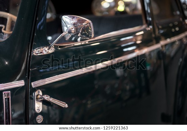 Vintage chrome car with side mirror and\
side door handle. Classic black shiny paint with reflection after\
polishing. Concept of classic car and retro\
style