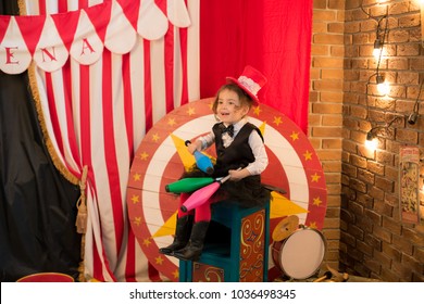 Vintage circus. Smiling funny baby girl in a red hat cylinder  in front of the circus tent. - Powered by Shutterstock