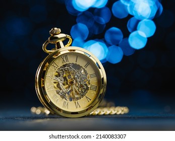 Vintage Clock, Alarm Clock In Gold Color On A Dark Blue Background With Lights. Minimalism. There Are No People In The Photo. Retro Style, Interior Design. Symbol Of Time, History.