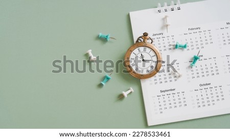 vintage clock and grunge white yearly calendar, green thumbtack on grunge green background with copy space, business meeting schedule, travel planning or project milestone and reminder  concept