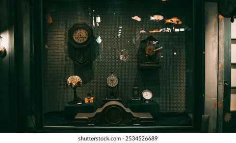 Vintage clocks and a stained-glass lamp adorn a dimly lit display window, casting warm reflections against a textured backdrop. - Powered by Shutterstock