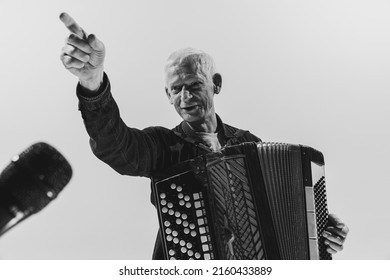 Vintage club music. Monochrome portrait of seniot man, retro musician playing the accordion isolated on white background. Concept of art, music, style, older generation, vintage