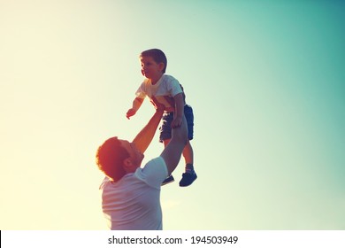 Vintage Color Photo Happy Joyful Father Having Fun Throws Up In The Air Little Boy Child, Family, Travel, Vacation, Father's Day - Concept. Sunlight On The Sunset Background