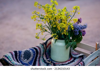 Vintage Colorful Handmade Rug And Yellow Spring Flowers In Watering Can. Country Life, Cottage Core, Creative Rustic Patchwork Concept