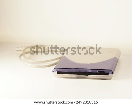 Vintage computer technology: external 3.5 inch USB-A floppy disk drive (FDD) in apple design with silver cable