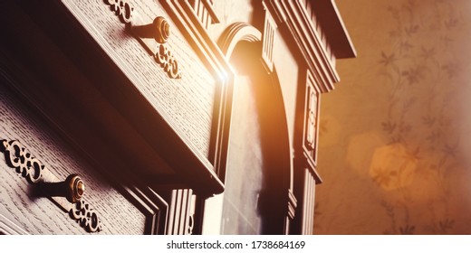 Vintage Dark Wooden Chest Of Drawers With Metal Handles And Orange Sunlight Reflection Extreme Close Low Angle Shot