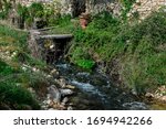 Vintage destroyed house in a forest. Old stone mill and a water stream with waterfall.