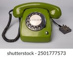 Vintage dial telephone. Isolated olive green telephone on gray background. Old fashioned technology. 