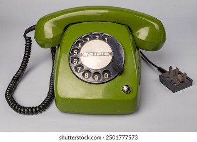 Vintage dial telephone. Isolated olive green telephone on gray background. Old fashioned technology. 