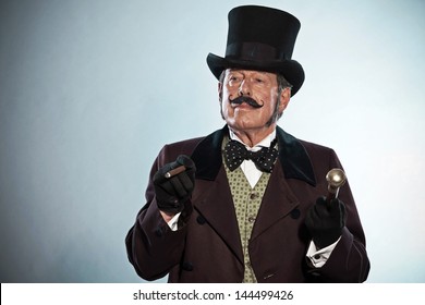 Vintage dickens style man with mustache and hat. Smoking cigar. Studio shot.