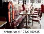 Vintage diner featuring red leather booths, chrome tables, and an old-school jukebox Stools and counters aligned for customers inside cozy restaurant setting with a nostalgic theme