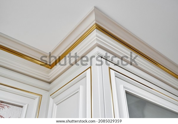 Vintage display case with crown molding and glass\
door in classic style and vintage wall panel with golden molding in\
light spacious room\
closeup