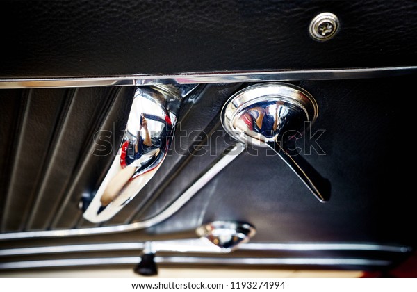 The vintage door panel in classic car interior.\
Classic stainless steel door handle. Chrome, trim and upholstery.\
Selective focus.