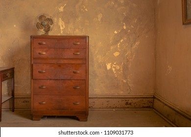 Vintage Dresser Sitting Alone In An Old Worn Room Of An Abandoned Home With Old Time Fan And Peeling Paint In Ohio