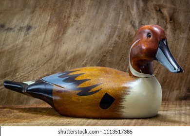 Vintage duck decoy on a wooden table with a wooden background