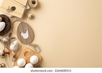 Vintage Easter concept. Top view photo of rustic decor easter eggs in wooden holder nest ceramic bunny drawing block paintbrushes twine and quail feathers on isolated beige background with empty space - Powered by Shutterstock