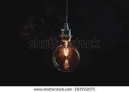 Vintage edison lightbulb on dark background with bright yellow shining wire