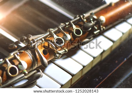 Vintage effect photograph. Antique clarinet leaning on piano keyboard.