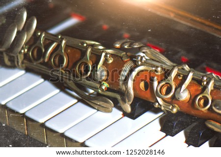 Vintage effect photograph. Antique clarinet leaning on piano keys.