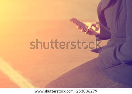 Vintage effected photo of woman use mobile phone in the city