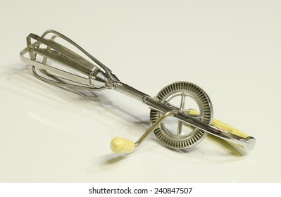 A Vintage Egg Beater On A White Surface