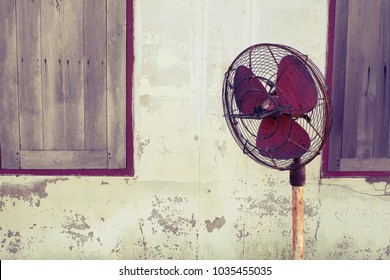 Vintage electric fan,old red electric fan at old wall next to wood window with copy space