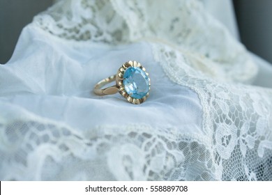 Vintage Engagement Ring With Aquamarine Stone Over A White Lace Cloth