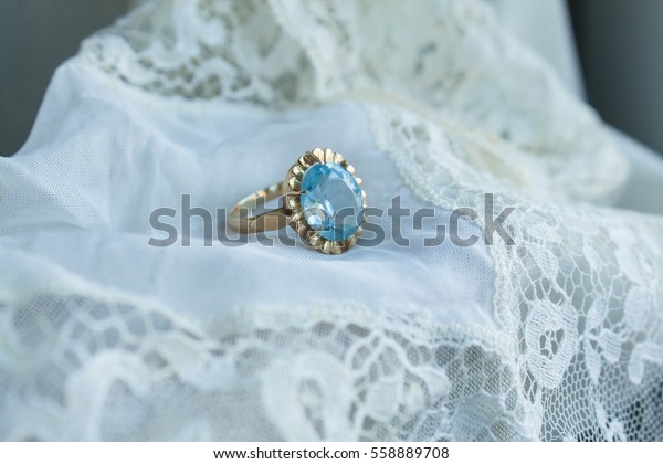 vintage engagement ring with aquamarine stone over\
a white lace cloth
