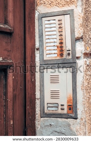Vintage entry intercom system on an aged building facade. Concept of classic European architecture, residential access, retro security, and urban history. Vertical image.