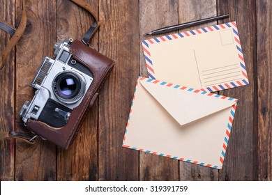 Vintage Envelope With Post Card And Retro Camera On Old Wooden Table