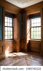 Vintage european interior, corner of the room with windows on both sides. Wood panelling interior design. Historic manor with parquet floor. Romantic antique residence. Luxury style