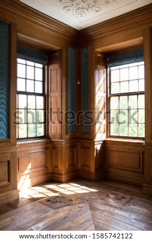 Vintage european interior, corner of the room with windows on both sides. Wood panelling interior design. Historic manor with parquet floor. Romantic antique residence. Luxury style
